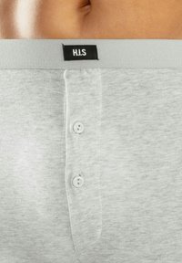 Hallhalli puuvillased bokserid halli värviga, varustatud nööbiga sulgemisega, elastse vöökohtaga, millel on "H.I.S" silt, ning sile tekstuur, millel on kerge helesinise mustriga. 
