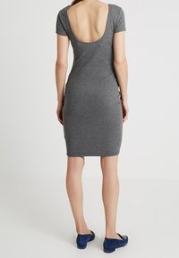 Gray fitted dress with short sleeves and a deep back cut, made from soft fabric. Paired with blue flats. Simple, smooth texture.