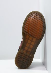 Czarne buty wsuwane z wzorzystą tekstylną cholewką, gumową podeszwą z fakturowanym bieżnikiem i widoczną marką na wkładce.