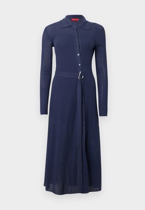 Riflové modré šaty s dlouhými rukávy, zapínáním na knoflíky vpředu a páskem v pase se stříbrnou sponou. Mají límec a celoplošný střih.