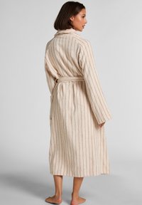 Beżowy szlafrok w paski o miękkiej teksturze, z długimi rękawami i wiązanym paskiem. Posiada pionowe paski w kontrastowym kolorze jako element dekoracyjny.