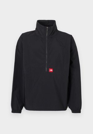 Veste noire à demi-fermeture éclair avec col montant, poignets élastiques et un écusson logo rouge. Elle présente une texture légère et lisse ainsi qu'une coupe décontractée.
