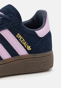 Blå ruskinn sneaker med rosa striper, med gull "SPEZIAL" tekst og en teksturert brun såle. Rund form, polstret krage detaljer.