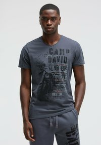 Graues Kurzarm-T-Shirt mit gemischter Typografie und grafischem Druck, V-Ausschnitt-Design und weicher, baumwollähnlicher Textur.