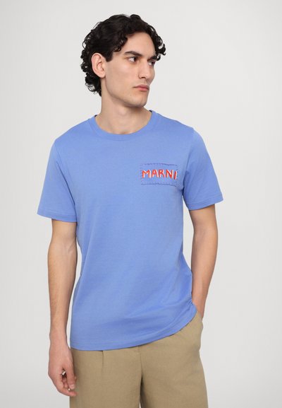 T-shirt en coton bleu clair avec des manches courtes. Présente une poche sur la poitrine avec le mot "MARNI" brodé en rouge et des détails de couture contrastants.