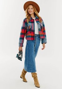 Bavlnená zmes, v mnohých farbách károvaná bunda s gombíkovým zapínaním a prednými vreckami, skombinovaná s modrou džínsovou sukňou a béžovými čižmami po kolená.