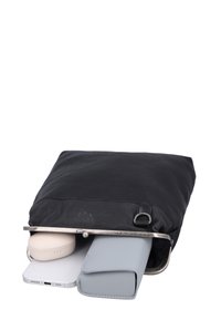 Schwarze Lederhandtasche leicht geöffnet, zeigt ein weißes Smartphone, eine graue Brieftasche und ein beiges ovales Etui innen.