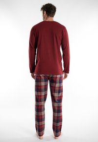 Heren nachtkledingset met een effen bordeauxrode long-sleeve top en geruite broek in rood, blauw en crème, gemaakt van een zachte stof.
