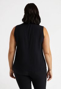 Top senza maniche nero con una texture liscia e una vestibilità comoda, che offre un design semplice senza hardware o motivi visibili.