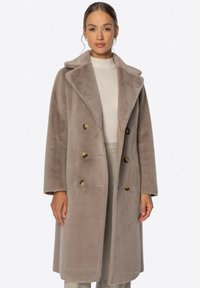 Doppelreihiger Mantel aus weichem, hellen Taupe-Stoff mit einer plüschigen Textur, breiten Revers und Knöpfen in Goldfarbe. Lange Ärmel und knielanger Schnitt.