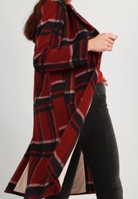 Cappotto a quadri in tessuto rosso, nero e grigio; design con apertura frontale; maniche lunghe; fodera beige a contrasto; dettaglio orlo curvo.