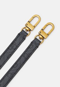 Dwa czarne teksturowane skórzane paski z złotymi metalowymi zapięciami obrotowymi na białym tle.