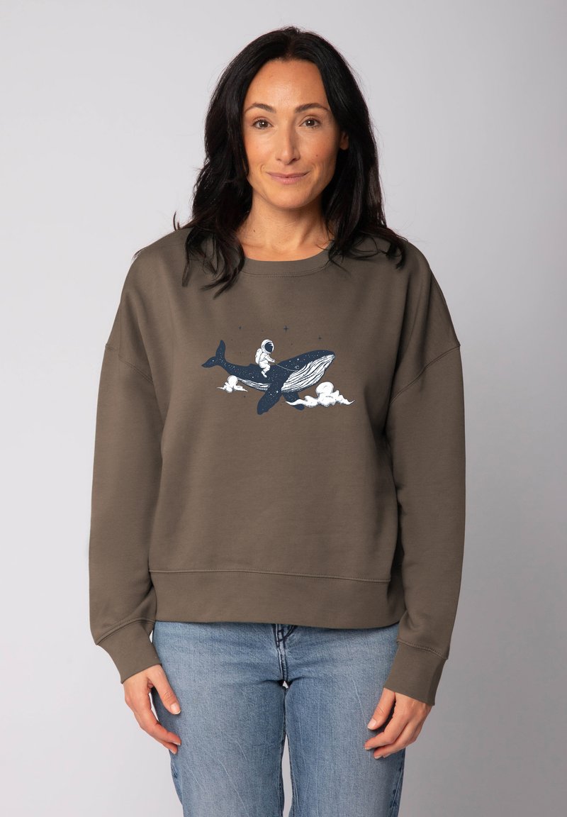 Bruine sweatshirt met een losse pasvorm, met een witte en marineblauwe afbeelding van een astronaut die op een walvis rijdt tussen de wolken. Zachte, gestructureerde stof.