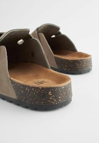 Des sandales en suède gris avec un coussin en liège, une semelle bicolore mouchetée et un design ouvert à l'avant. Comprend des accents découpés sur les tiges.