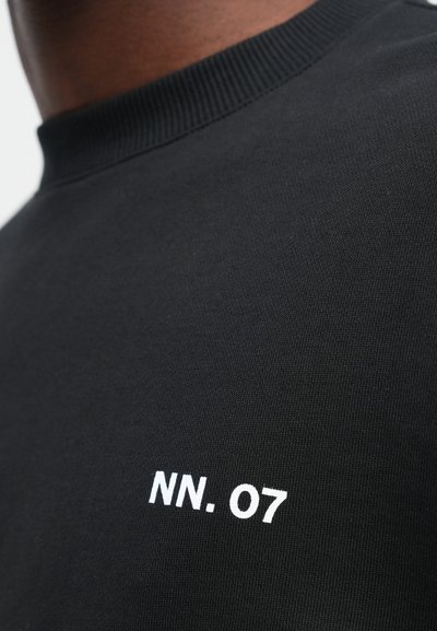 Černá mikina s ribovaným výstřihem a jemně texturovanou látkou. Na přední straně se nachází bílé vyšívání "NN. 07".