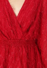 Vestito rosso con scollo a V, tessuto testurizzato con fili metallici e vita elastica arricciata per un effetto increspato.
