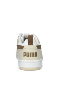 Sneakers Puma in beige e bianco con un accento marrone. Presentano un materiale testurizzato, colletto imbottito e un logo del brand ben visibile sul tallone.