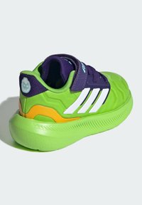 Bright green athletic shoe with a textured design, purple accents, and white stripes. Features a hook-and-loop strap and a chunky sole.
