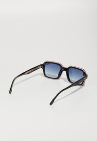 Ochelari de soare pătrați cu rame din plastic negru, lentile cu gradient albastru și accente roșii de-a lungul marginii. Brațele prezintă detalii din metal auriu.