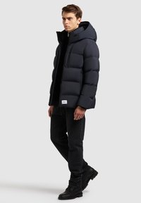 Tengerész kék pehelykabát kapucnival, elől cipzárral záródik, két oldalsó zsebe van, és a szegélye mellett logófelvarró található. Fekete farmernadrággal és csizmával viselik.