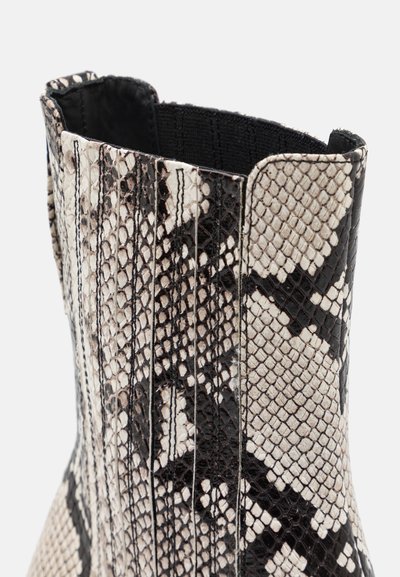 Ankle boot in a black and white snake print. Features textured material with vertical ribbed detailing and an elasticized top.
