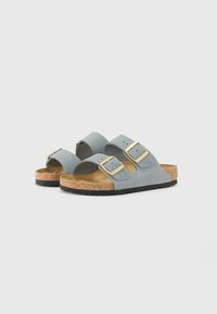 Sandali in suede grigi con due cinturini regolabili, fibbie dorate, soletta in sughero e suola in gomma nera. Design minimalista con punta aperta.