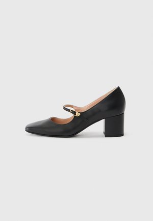 Black leather Mary Jane shoe with a pointed toe, ankle strap featuring a gold buckle, and a stacked block heel. Smooth texture.