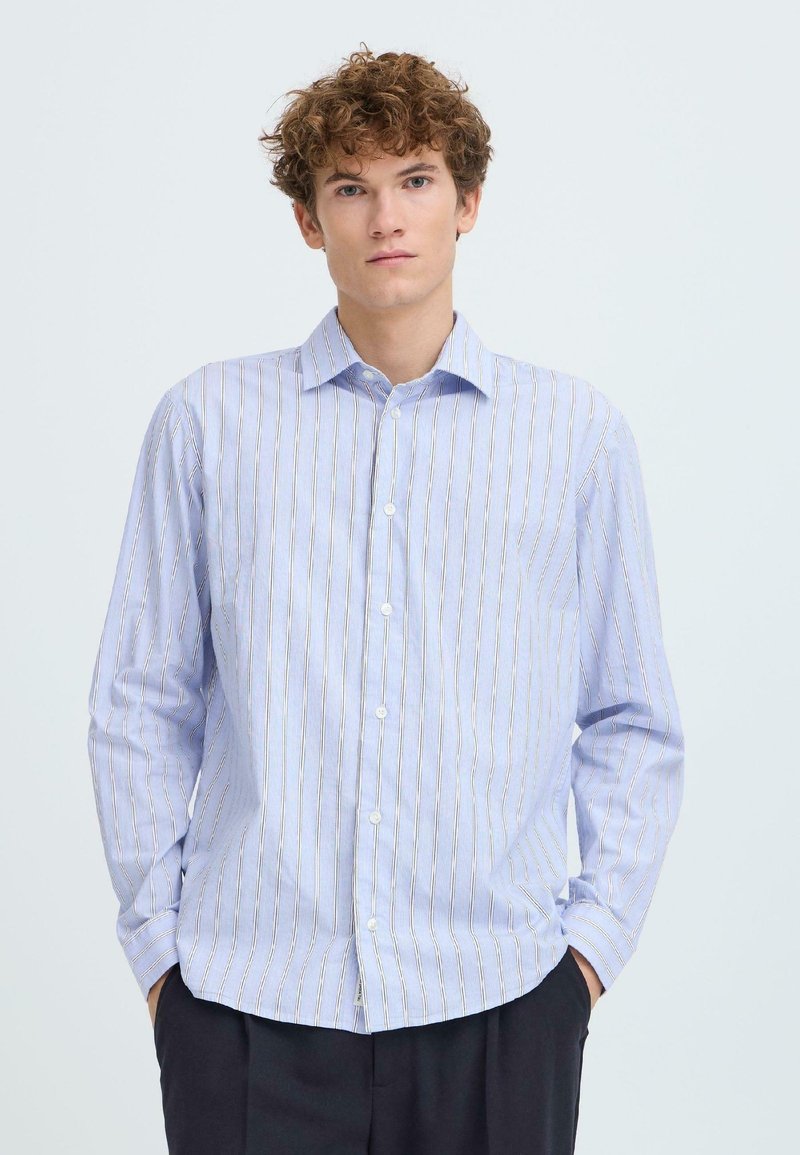 Ανοιχτό μπλε πουκάμισο με μακριά μανίκια και κάθετες ρίγες σε λευκό και κίτρινο. Διαθέτει μυτερό γιακά και κλείσιμο με κουμπιά, κατασκευασμένο από λείο βαμβακερό ύφασμα.