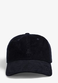 Gorra de pana marina con visera curvada, que presenta un sutil detalle bordado de calavera y huesos cruzados en la parte frontal, con textura de tela visible.