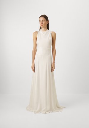 Robe longue sans manches en ivoire, fabriquée à partir d'un tissu léger et fluide. Présente un col haut et un corsage ajusté, s'évasant en une jupe ample.