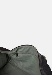 Schwarze Stofftasche mit einem weichen grünen Futter, ausgestattet mit einer Reißverschlusstasche, sichtbarem Reißverschluss und stabilen Kanten.