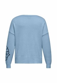 Maglione azzurro chiaro con orlo e polsini a coste. Presenta un motivo floreale nero sulla manica sinistra. Tessuto morbido, vestibilità rilassata.