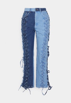 Denim jeans featuring a split design in dark and light blue, with decorative lacing along the side seams and ties at the hem.