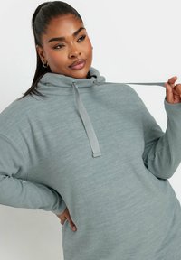 Överdimensionerad, ljusgrå hoodie med ribbade ärmar och snörning vid halsen. Mjuk textur och avslappnad passform.