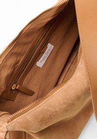 Indvendig i den tan-farvede ruskinds-totepose er der en lynlås lomme og et mærke med påskriften "Part Two Copenhagen". Den har en glat tekstur og sydd kanter.