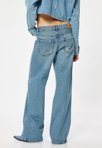 Ljust blå denim byxor med vida ben och hög midja, med dubbla bakfickor och råtkant nederst.