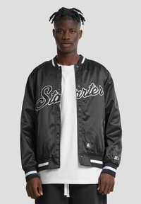 Veste bomber en satin noir avec le logo "Starter" blanc, des poignets côtelés rayés, des boutons pression et un patch sur la manche gauche.