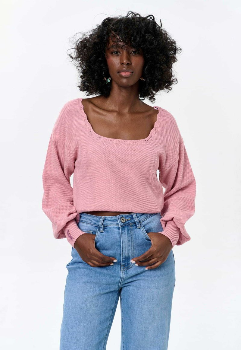 Roze gebreide trui met een vierkante halslijn, losse mouwen en een textuur, gecombineerd met hoogwaist lichtblauwe denim jeans.