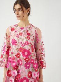 Genomskinlig rosa blus med blomsterbroderier i livliga röda och rosa nyanser, med trekvartslång ärm och rund halsringning.