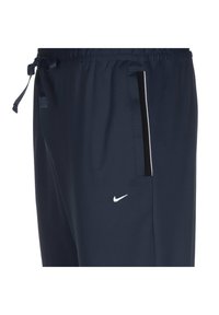 Navy Jogginghose aus leichtem Material. Mit einem Kordelzugbund, Seitentasche mit schwarzem Besatz und einem kleinen weißen Logo.