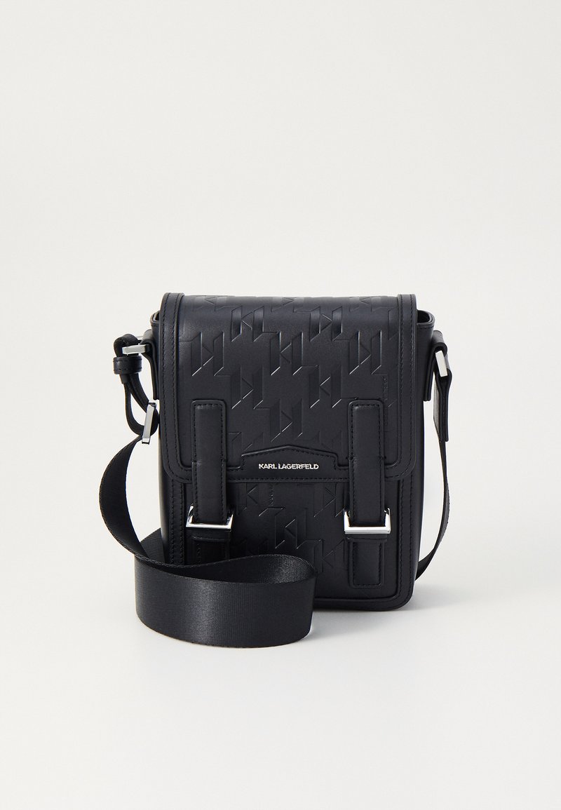 Borsa a tracolla in pelle nera con motivo embossato, hardware in argento e tracolla regolabile. Caratterizzata da una chiusura a patta e logo del marchio frontale.