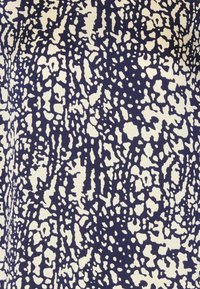 Tessuto blu navy e crema con un motivo astratto testurizzato caratterizzato da forme irregolari e dimensioni variabili, creando profondità visiva e contrasto.