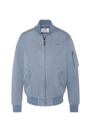 Veste bomber bleu clair avec fermeture éclair à l'avant, col et poignets côtelés, deux poches latérales et une poche zippée sur la manche gauche.
