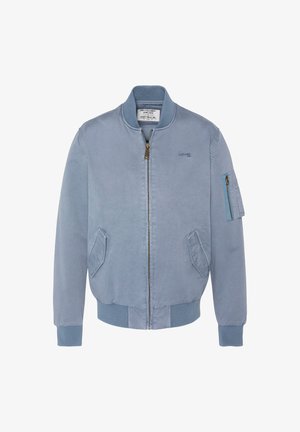 Veste bomber bleu clair avec fermeture éclair à l'avant, col et poignets côtelés, deux poches latérales et une poche zippée sur la manche gauche.