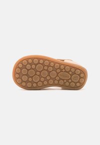 Suola di una scarpa con un motivo testurizzato a pois di colore marrone chiaro e con il nome del marchio "bisgaard" impresso.