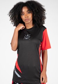 Zwart en rood sportshirt met korte mouwen en ronde hals, met een grafisch logo in zilver op de voorkant en rode accenten aan de zijkanten.