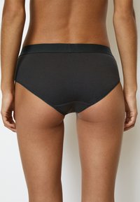Mutande nere a costine con un design a vita alta. Presentano un elastico in vita liscio e una finitura senza cuciture lungo le aperture delle gambe per un comfort ottimale.
