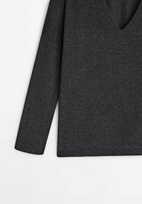 Pull gris charbon avec un col en V, manches longues et tissu doux et texturé. Il présente un ourlet droit et une finition côtelée aux poignets.