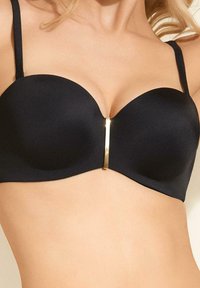 Czarny stanik ze wzmocnionymi miseczkami, gładką tkaniną i centralnym złotym paskiem. Regulowane ramiączka dopełniają całość.