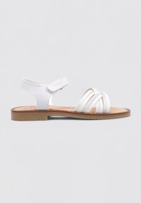 Sandalia blanca con tira ajustable, que presenta tiras en cruz diagonales y una suela de color marrón claro. Textura suave con ligeros acentos de brillo.